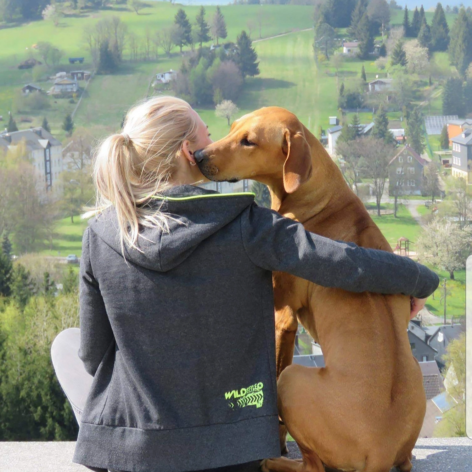 Frau umarmt ihren Hund mit Blick über die Thüringer Landschaft – Hundebegleitung in Thüringen